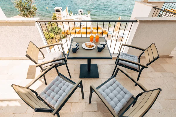 Croissants e suco recentemente espremido, mobiliário de jardim na varanda com vista para o mar . — Fotografia de Stock