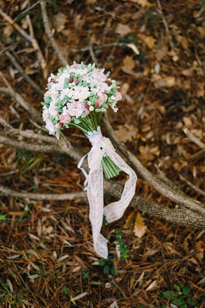 Ramo nupcial de rosas blancas y rosas, bayas silvestres, eustoma con cintas de encaje blanco en el brunch seco, liyng en el suelo — Foto de Stock