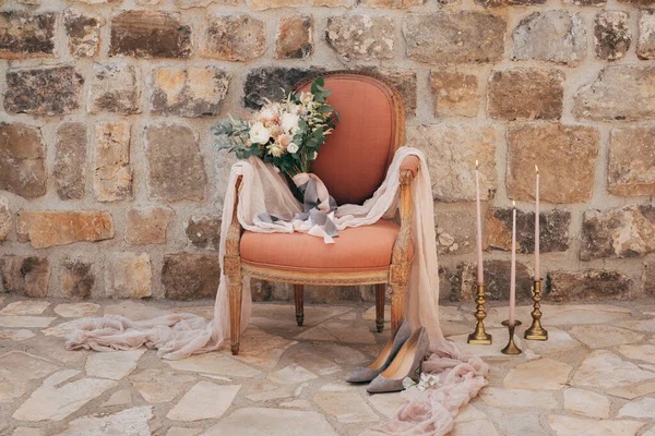 Bukiet ślubny białych i kremowych róż, gałęzie eukaliptusa drzewa, różowe i szare wstążki w fotelu buty panny młodej w pobliżu niego — Zdjęcie stockowe