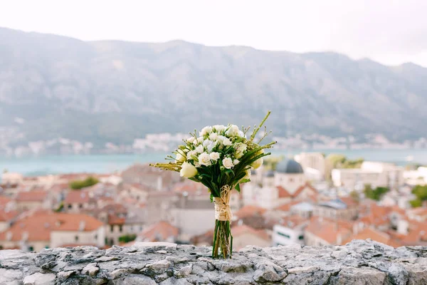 Bridal bouquet of white roses and hipsalis on the stone wall with the view of the Old city of Kotor — Stock Photo, Image