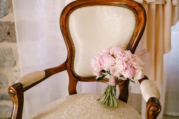 Ramo nupcial de peonías rosadas y cintas rosadas en el elegante sillón de la habitación —  Fotos de Stock