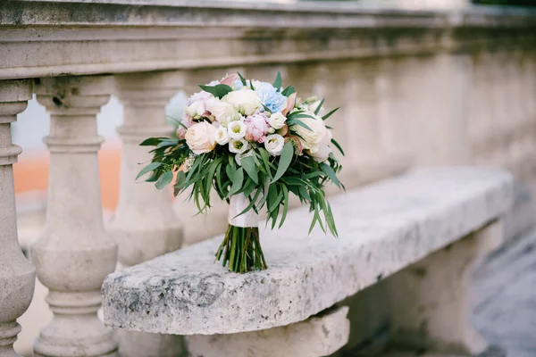 Ramo nupcial de rosas blancas y rosadas, peonías, ramas hortensas de eucalipto, eustoma y cintas blancas en el banco de piedra cerca de la barandilla de una antigua escalera —  Fotos de Stock