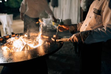 Aşçı ızgaradaki bir termometreyle bifteğin sıcaklığını ölçer..