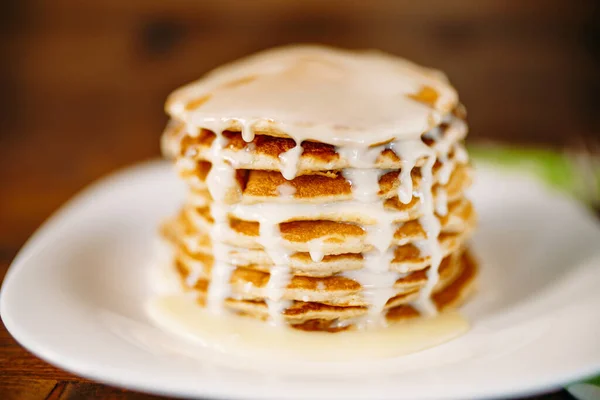 Gecondenseerde melk die op een stapel pannenkoeken wordt gegoten. — Stockfoto