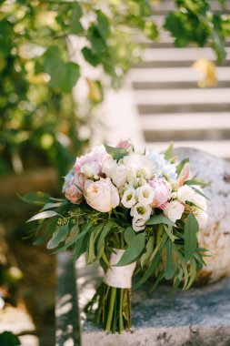 Gelinlik buketi beyaz ve pembe güller, şakayıklar, okaliptüs ağacının korkunç dalları, östoma ve beyaz kurdeleler antik bir merdivenin korkuluğunda.