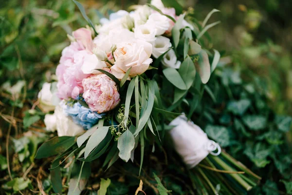 Bouquet de roses blanches et roses, pivoines, branches corsées d'eucalyptus, rubans blancs d'eustome et alliances sur fourrés de lierre — Photo