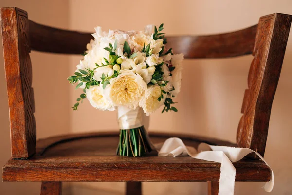 Ramo nupcial de rosas blancas, freesia, ramas de boj y cintas blancas en la silla de madera —  Fotos de Stock