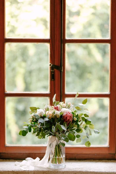 Ramo nupcial de peonías blancas, rosas, proteas rosadas, bayas de nieve, ramas de eucalipto y cintas blancas en la ventana —  Fotos de Stock