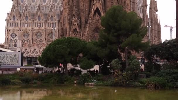 Η πρόσοψη των Χριστουγέννων της Sagrada Familia, μια άποψη της εκκλησίας από το πάρκο. Κατασκευαστικοί γερανοί χτίζουν το κτίριο. — Αρχείο Βίντεο