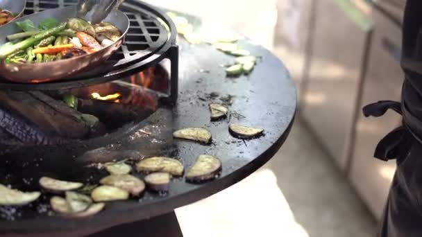 El cocinero tuesta los calabacines. Verduras a la parrilla. Parrilla redonda en forma de tazón con un fuego en el interior . — Vídeos de Stock