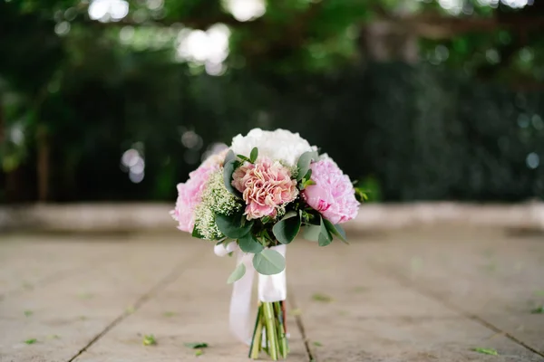 Buquê de noivas de peônias rosa e branca, ramos de eucalipto, ammi e fitas brancas ao ar livre — Fotografia de Stock