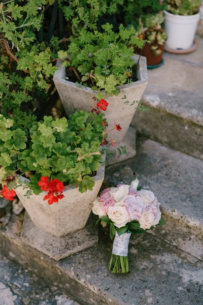 Bouquet nuptial de roses et de roses crème et de lis de calla sur les vieilles marches près des pots de géraniums — Photo