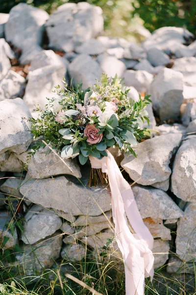 Bouquet nupcial de rosas brancas e rosa, eustoma, ramos de eucalipto e buxo, astilbe e fitas rosa sobre as pedras — Fotografia de Stock