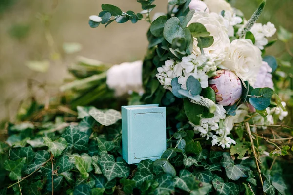 Buket pengantin merah muda dan putih peonies, mawar, cabang pohon eukaliptus, veronica, matthiola dan pita putih dengan kotak biru kecil, terlihat seperti buku, di semak ivy — Stok Foto