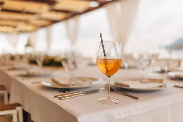 Glas met een oranje cocktail met ijs en een tube op de bankettafel. — Stockfoto