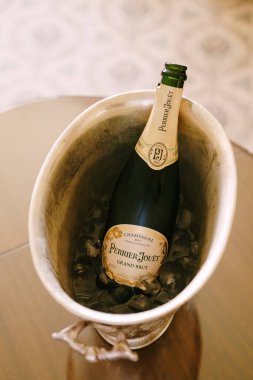Budva, Karadağ - 10 Haziran 2020: Masada buzlu metal bir vazoda bir şişe Perrier-Jouet Grand Brut.