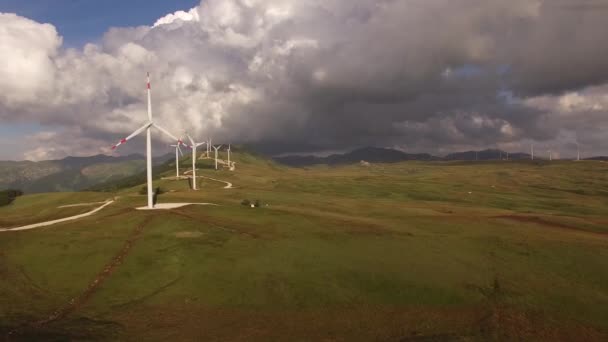 Foto aerea da un drone - una serie di enormi turbine eoliche lungo una strada su una collina tra le montagne in Montenegro. — Video Stock