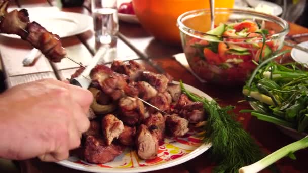 De kok legt de afgewerkte kebab in een bord. Geroosterd varkensvlees op een vuur. — Stockvideo