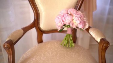Odadaki zarif koltukta pembe şakayık demeti ve pembe kurdeleler.