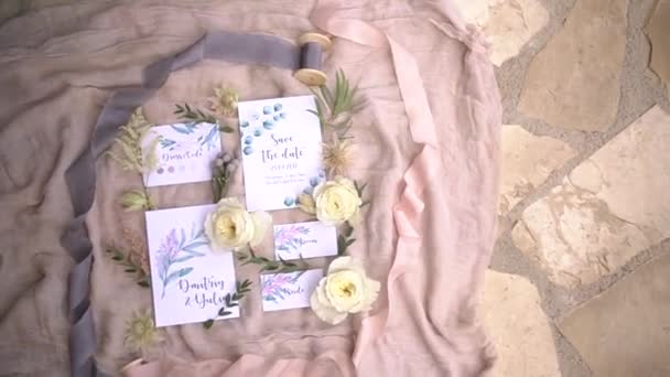 Весільна каліграфія - запрошення та кольорова карта коду красиво викладені на рожевій тканині з шовковими стрічками . — стокове відео