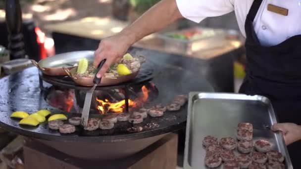 De chef grilt gehaktballen voor mini hamburgers op de grill. — Stockvideo