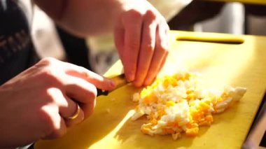 Şefin erkek eli, mutfak tahtasındaki bıçakla haşlanmış yumurtayı parçalara ayırdı..