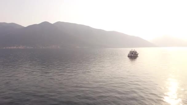 Jacht in de zee tegen de achtergrond van bergen en zonsondergang. — Stockvideo