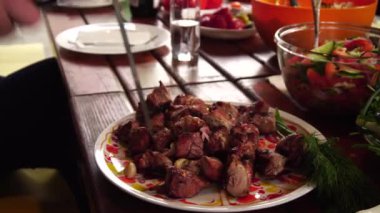 Aşçı bitmiş kebabı tabağa koyar. Kızarmış domuz eti ateşte.