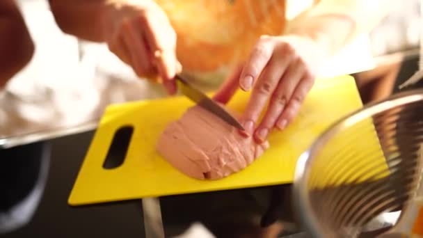 Mani delle donne tagliate salsiccia bollita con un coltello sul bordo della cucina. — Video Stock