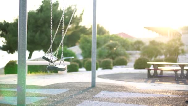 Swing en una cadena en el patio de recreo al atardecer . — Vídeo de stock