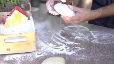 Şefin elleri yakın plan. Hamuru pizza için hazırlar, elleriyle yuvarlak şekillerde yuvarlanır..