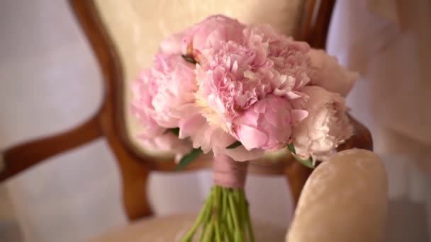 Bouquet nuptial de pivoines roses et rubans roses sur l'élégant fauteuil dans la chambre — Video