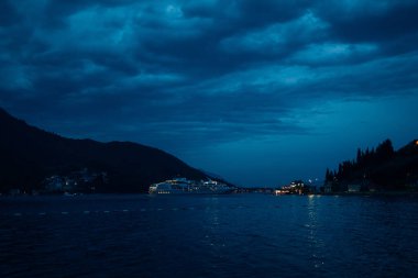 Gece yolcu gemisi, dağların arka planına karşı ve bulutlu gökyüzü bulutlu..