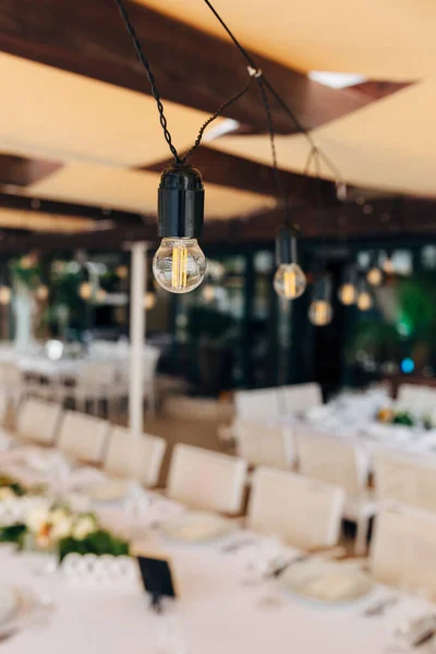 Garlands van LED-lampen boven een bankettafel voor een bruiloftsdiner. — Stockfoto