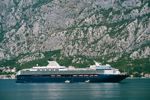 Огромный многопалубный круизный лайнер в Которском заливе, на фоне горы над городом Доврота и Люта в Черногории. — стоковое фото
