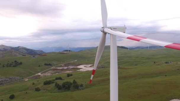 Close-up of wind turbine blades with red stripes against a green forest and field. — Stock Video
