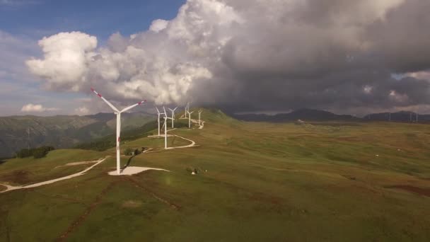 Luchtfoto van een drone - een serie enorme windturbines langs een weg op een heuvel tussen de bergen in Montenegro. — Stockvideo