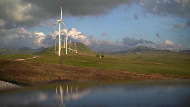 Řada větrných turbín na zelených kopcích v horách Černé Hory, proti zamračené deštivé obloze. — Stock video