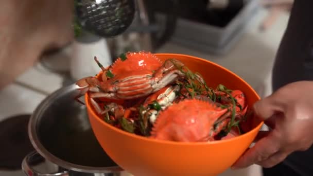 El cocinero saca los cangrejos rojos cocidos de la sartén y los pliega en un tazón de naranja. — Vídeos de Stock