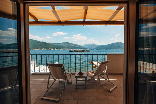 Two sun loungers on the balcony of the hotel room overlooking the sea and a passing tourist boat.