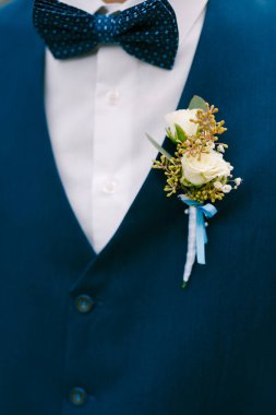 Mavi ceketli beyaz gül tomurcukları ve şık mavi papyon..