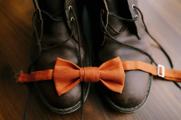 Ανοιχτό πορτοκαλί παπιγιόν γαμπρού σε ανδρικές μπότες. — Φωτογραφία Αρχείου