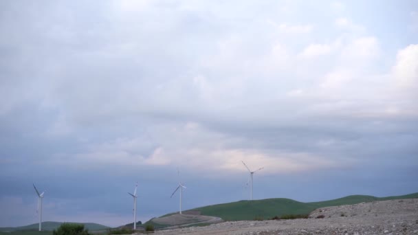 Um grande número de turbinas eólicas estão no campo ao pôr-do-sol, um horizonte com céu azul e nuvens de veludo . — Vídeo de Stock