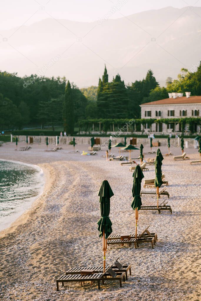 Wooden loungers on a sandy platform, at sunset. Villa Milocher in Montenegro, near the island of Sveti Stefan.