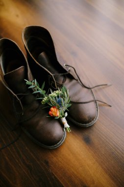 Damadın tomurcuğu kahverengi zeminin arka planına karşı erkek ayakkabılarına dayanır..