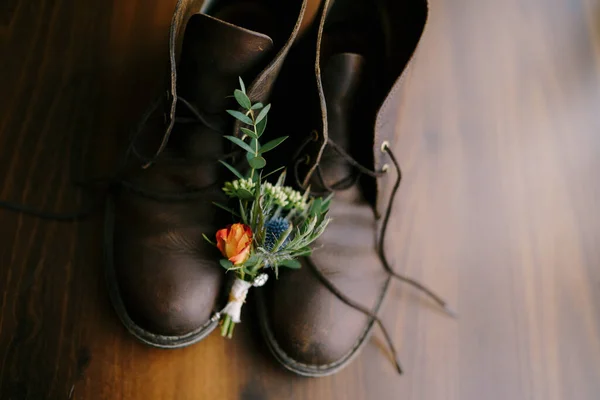 Un primer plano de brotes para el novio y zapatos para hombre sobre un fondo marrón . — Foto de Stock