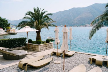 Tivat, Karadağ - 01 Temmuz 2020: Plastik plaj şezlongları. Karadağ 'ın Kotor Körfezi, Dobrota kenti. Hurma dallarının altında,. 