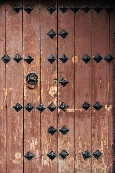 Braune Holztür mit Metallnieten und Türklopfer. — Stockfoto