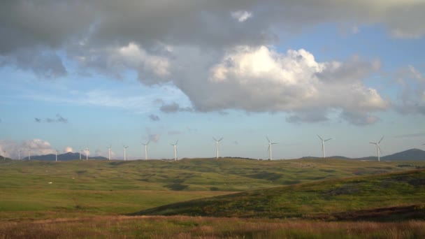 Ряд ветряных турбин на зеленых холмах в горах Черногории, против облачного дождливого неба. — стоковое видео
