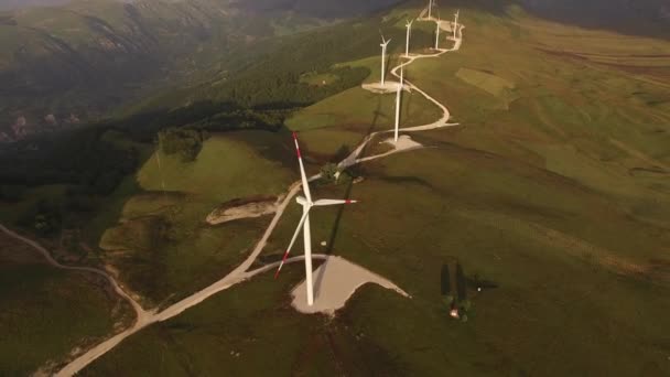 La perspectiva de una serie de altas turbinas eólicas industriales en la colina, contra el cielo azul y nubes blancas de terciopelo. — Vídeo de stock